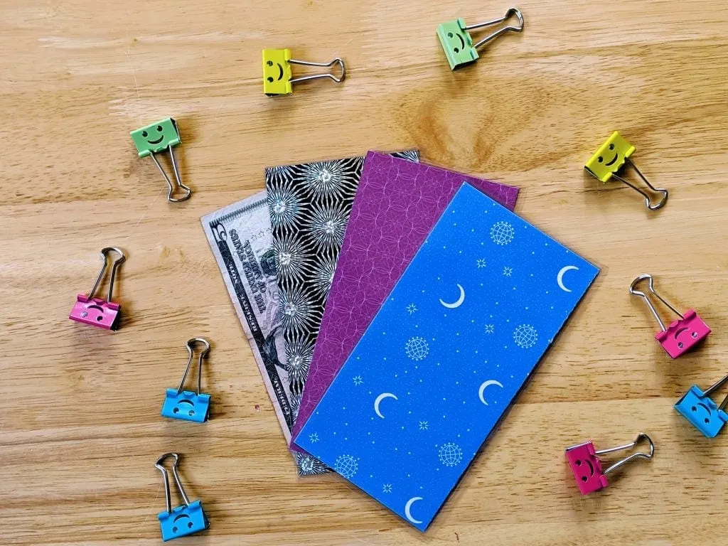 Colorful Laminated cash envelops and clips with smiley on wooden table
