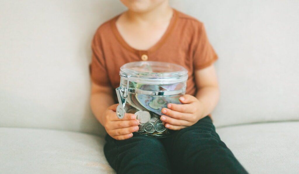 child holding a jar of money 