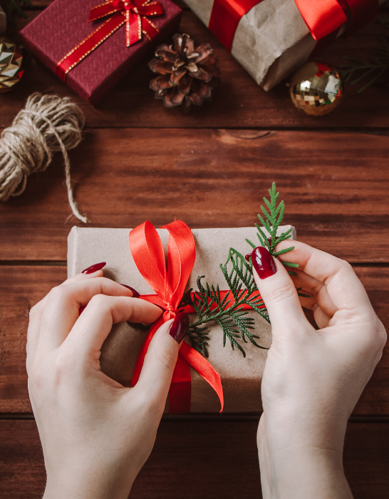 woman decorates a chirstmas gift with a ribbon