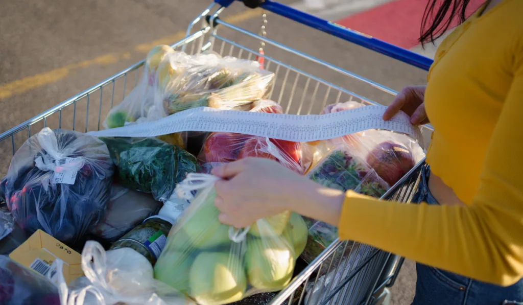 woman checks her grocery receipt at the parking lot