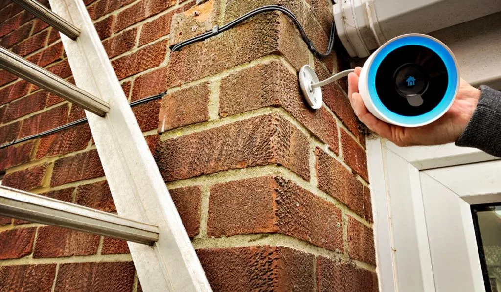 Close up view of a homeowner installing a Google Nest CCTV home security camera over the front door ee220326