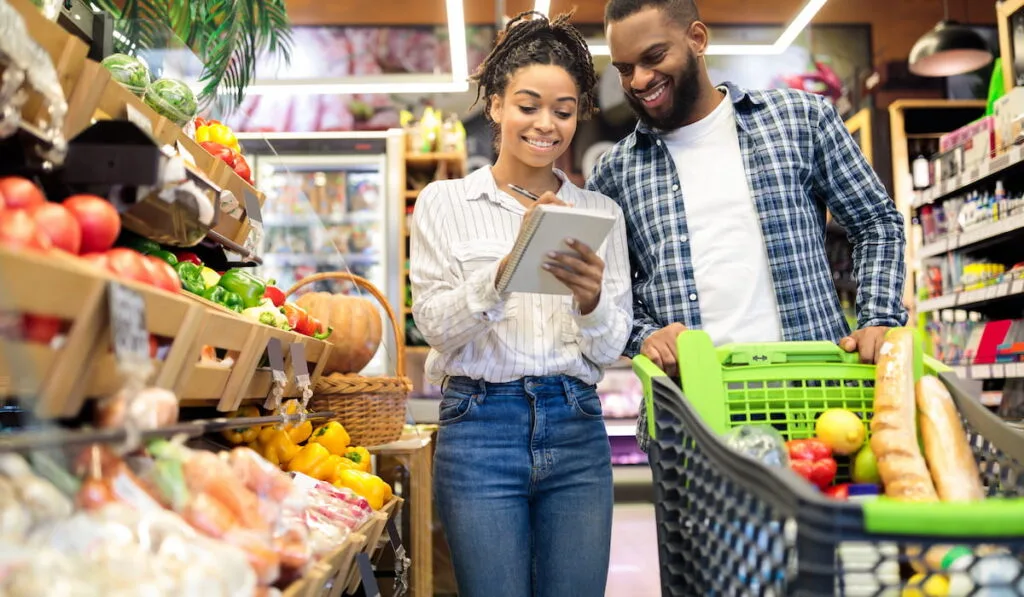 couple buying food and fruits taking notes in checklist 