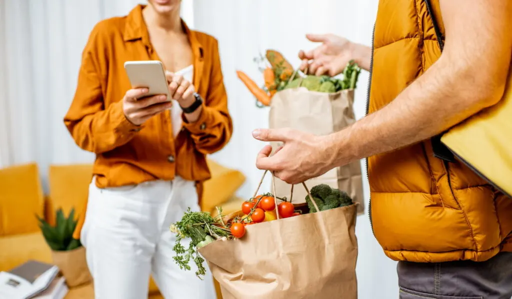 courier delivering bags of groceries at customer's home