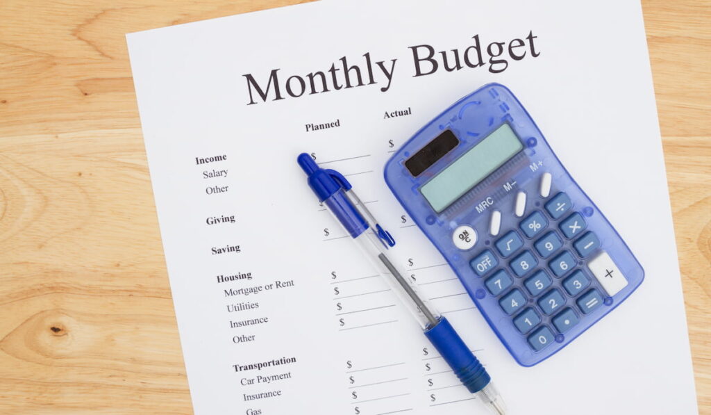 monthly budget list on paper with calculator and pen