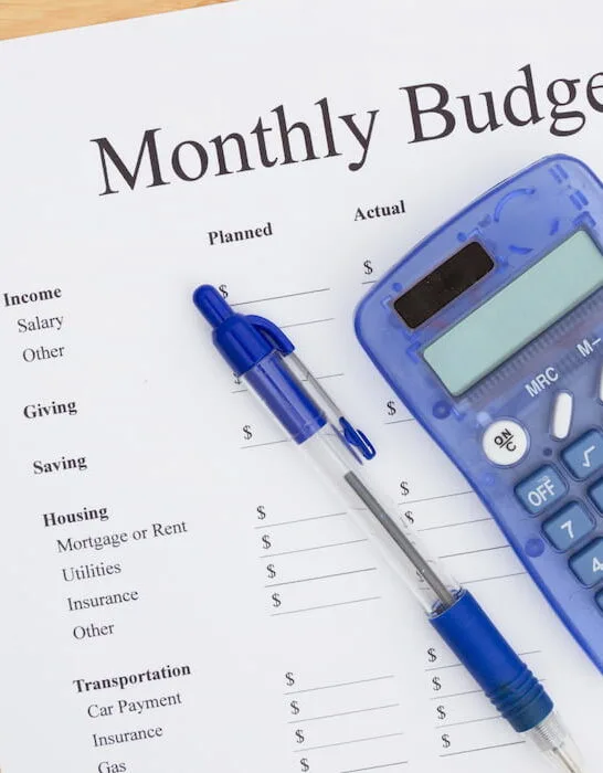 a pen, calculator and a monthly budget plan sheet