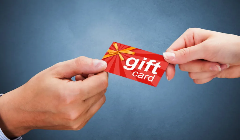 man and a woman holding a gift card