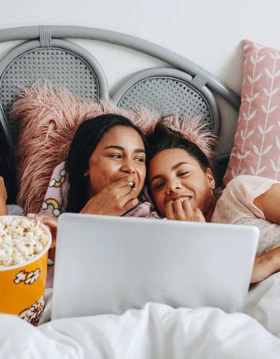 girls having sleepover, watching a movie with popcorn