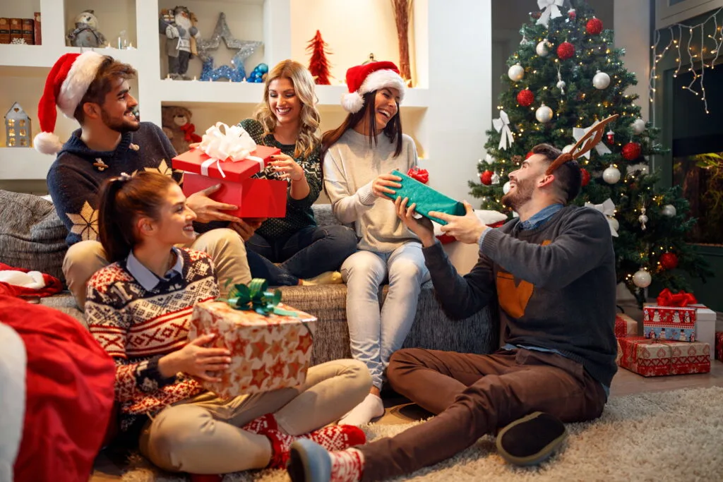 group of friends laughing and sharing Christmas gifts