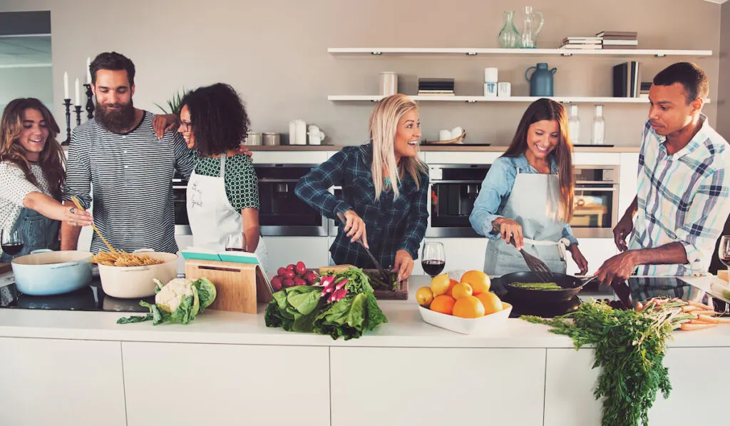 Group of friends cooking separately in the kitchen at home