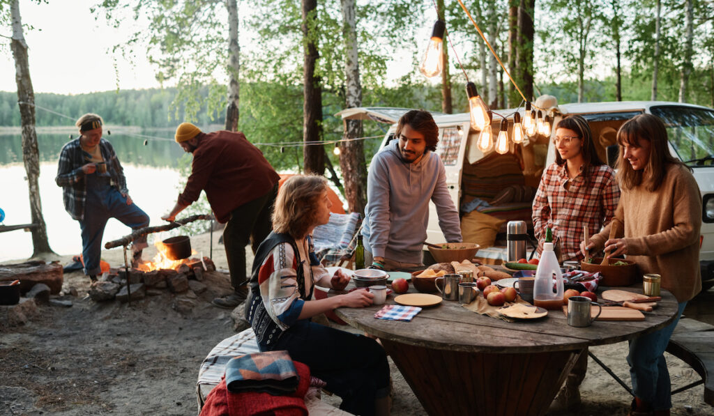Group of friends eating and talking together on a picnic in the forest

