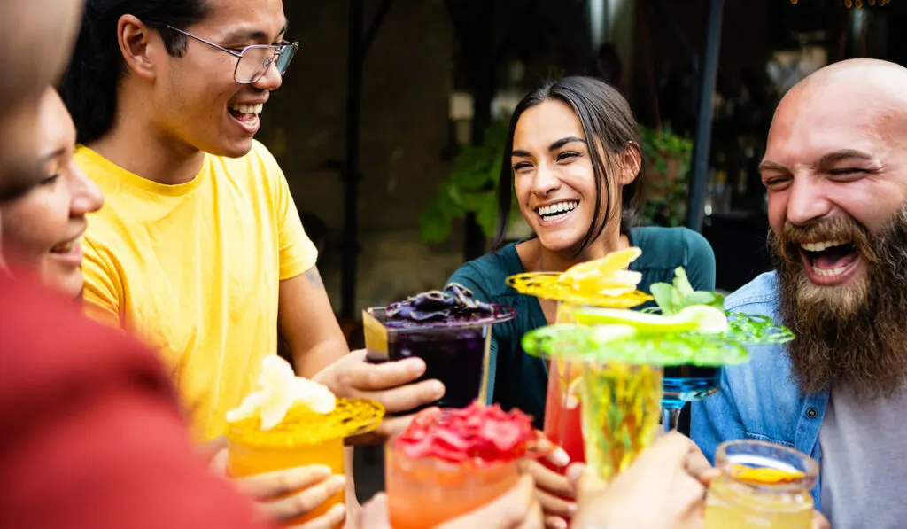 Happy group of friends drinking trendy cocktails