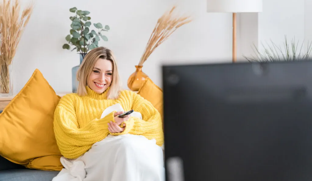 woman rewatching her favorite childhood movie at home
