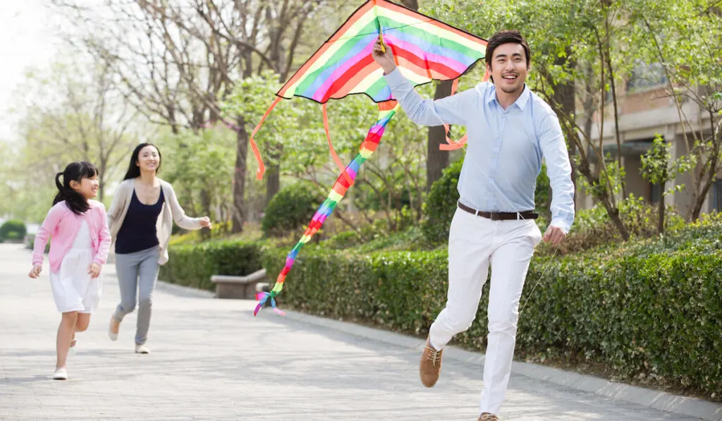 Happy young Chinese family flying a kite

