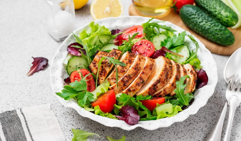healthy lunch vegetables salad with grilled chicken on white bowl
