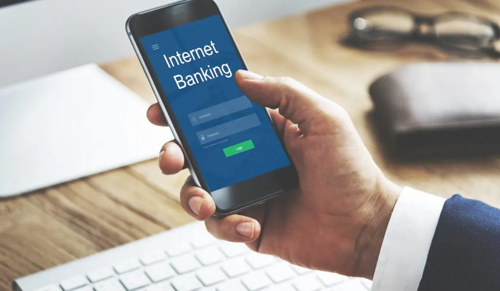 business man holding his cellphone doing an online banking transaction