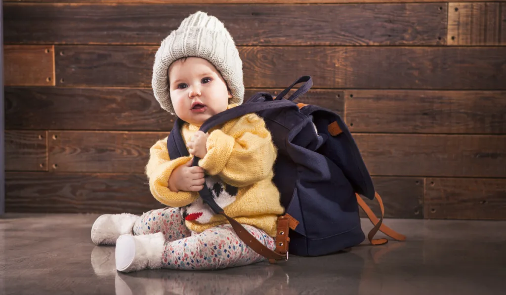 baby trying to grab her mommy's backpack