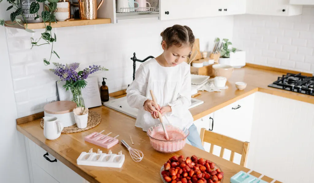 Little girl preparing homemade strawberry ice cream at the kitchen