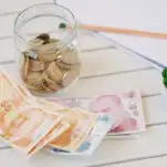 money jar with coins notebook and pen on the table