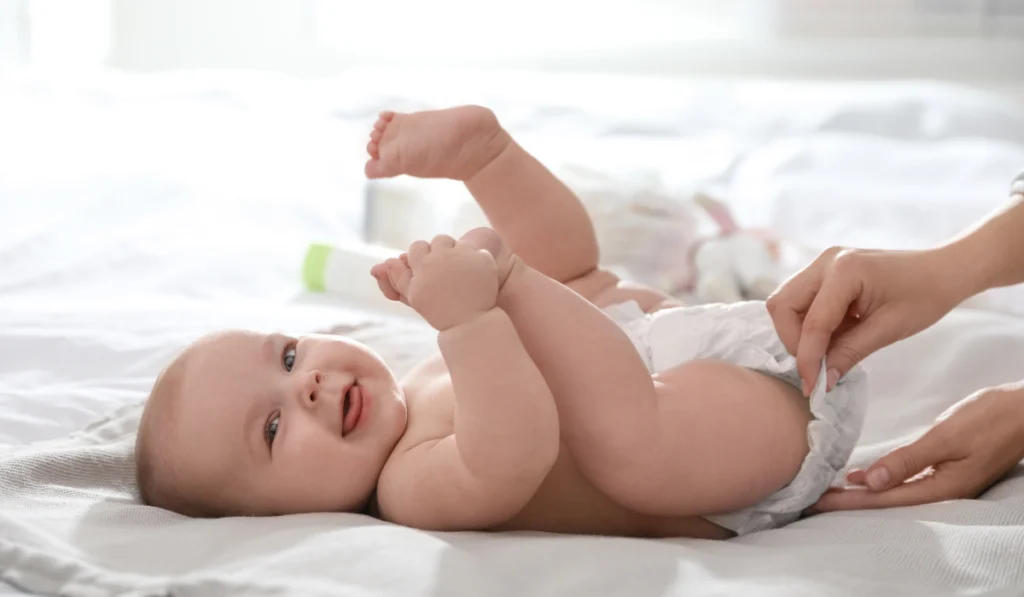 mother changing her baby's diaper on bed
