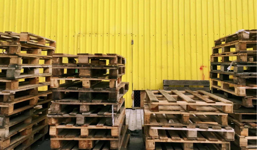 pallets in a parking lot with yellow steel walls