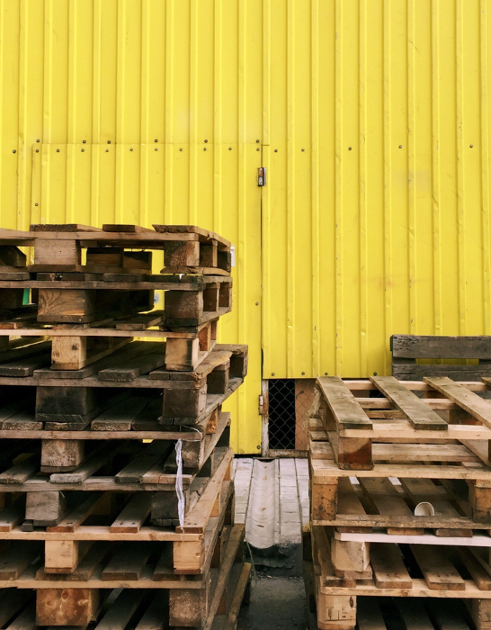 pile of pallets at a parking garage with yellow metal walls
