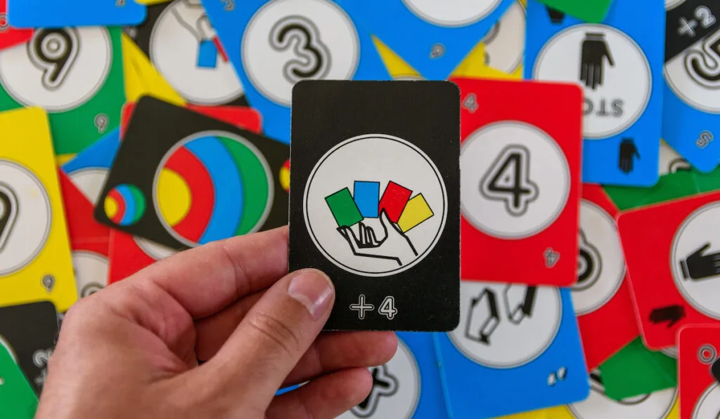 Personal perspective of hand holding black uno card with draw four sign
