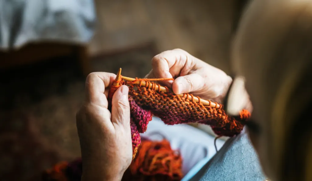 Senior woman knitting for hobby at home
