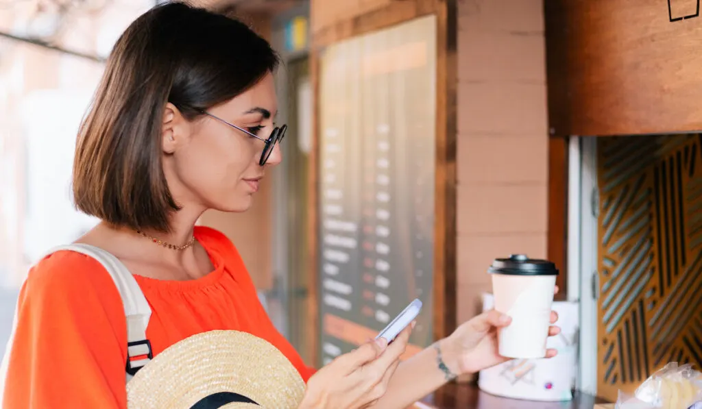 Woman buying coffee outdoor at coffee window

