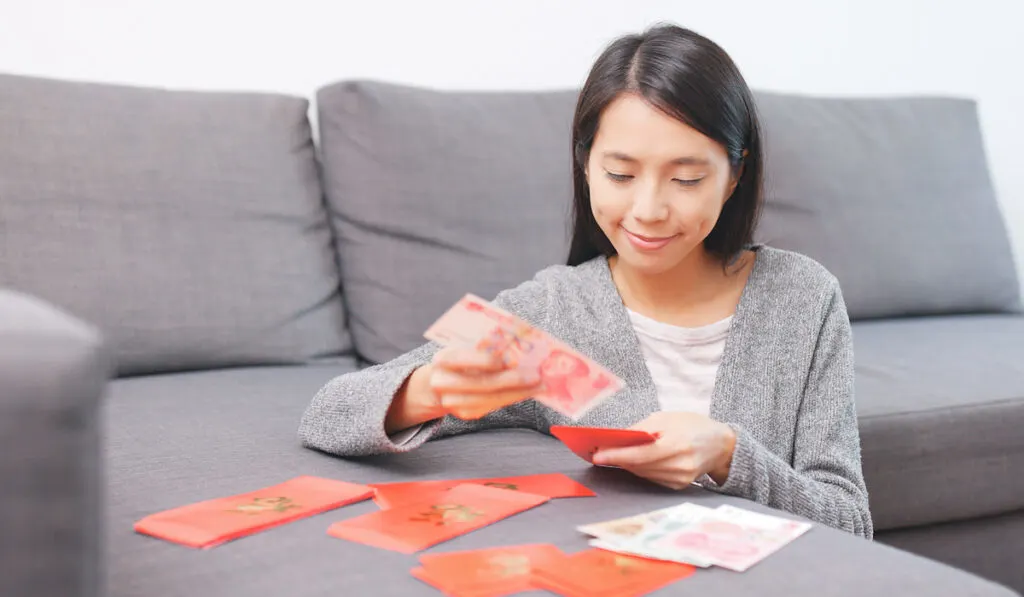 Woman putting money into chinese red packet

