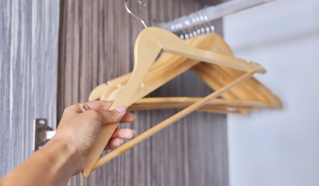 woman holding a wooden hanger organizing her closet