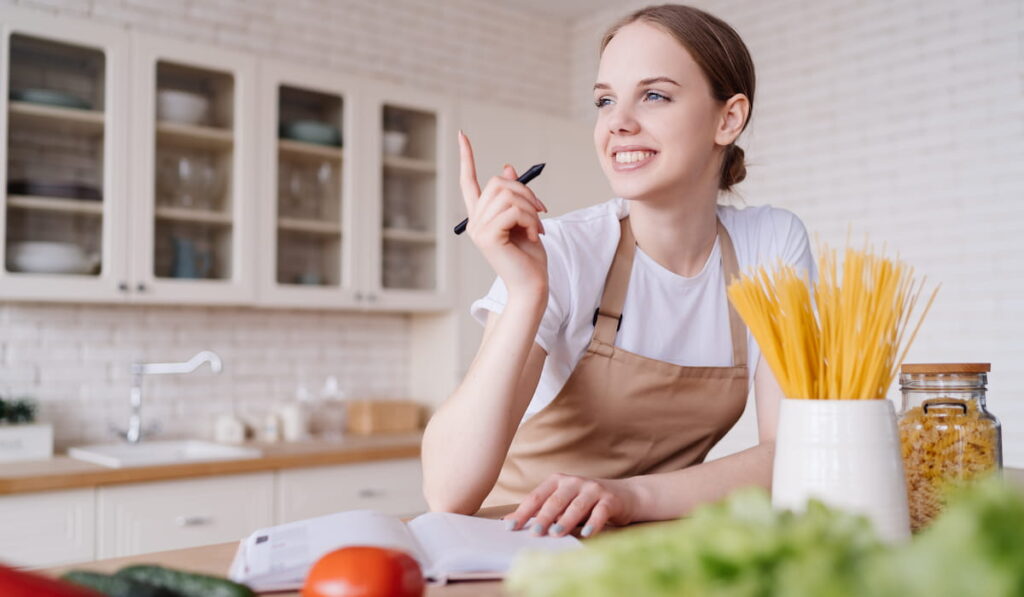 beautiful housewife in the kitchen writes down a meal plan for the family