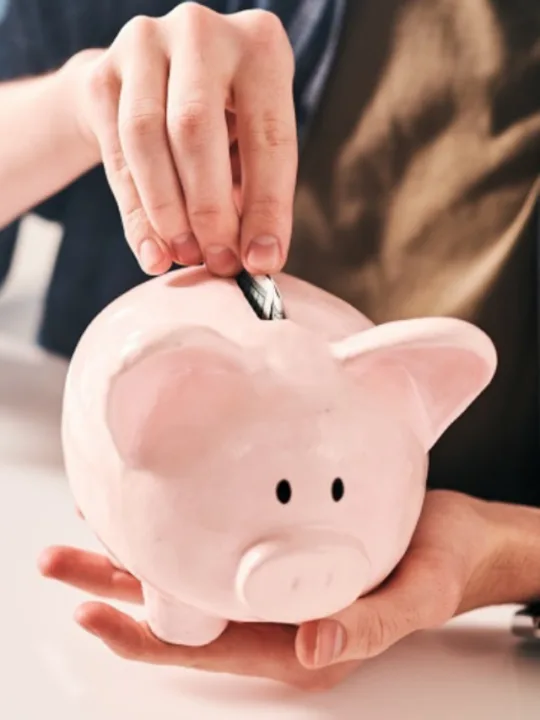 man-sitting-at-table-and-putting-coins-into-piggy bank