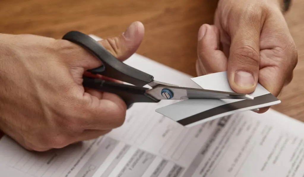 man cutting his credit card so he cannot use it