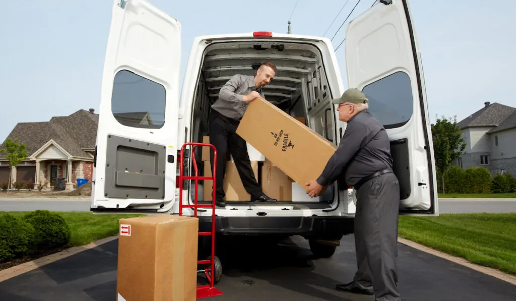 delivery man with a parcel unloading boxes from the truck