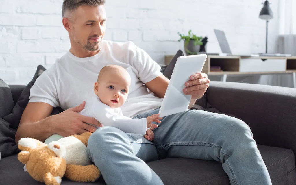 father sitting on couch with baby boy