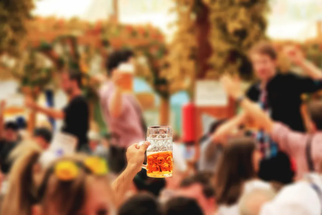 hand holding a mug of beer in Oktoberfest party blurry background 