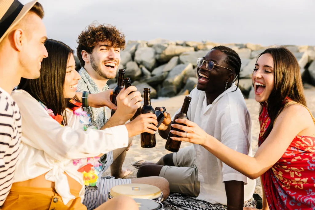 Happy friends enjoying weekend drinking and sitting by the beach