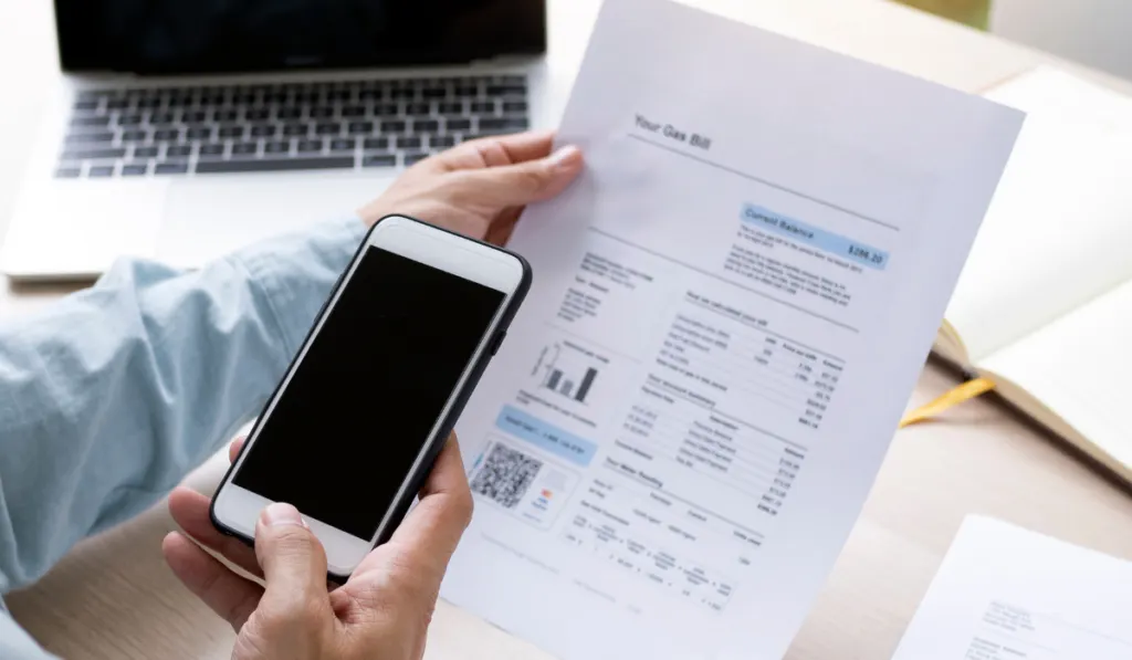 man checking his gas bill while holding his phone