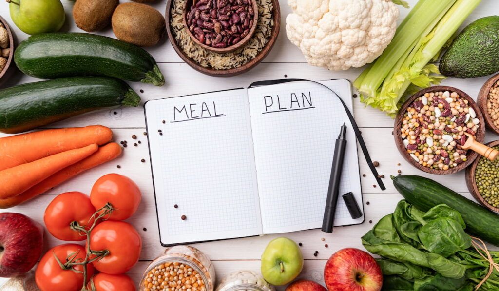 meal plan notebook with healthy food around it