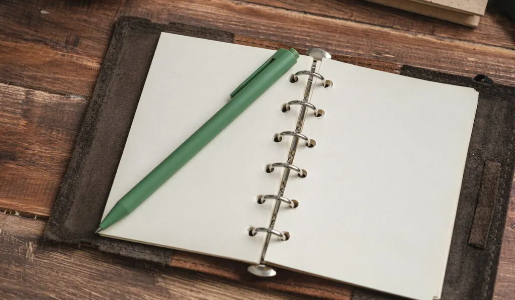 open blank planner with a green pen on top