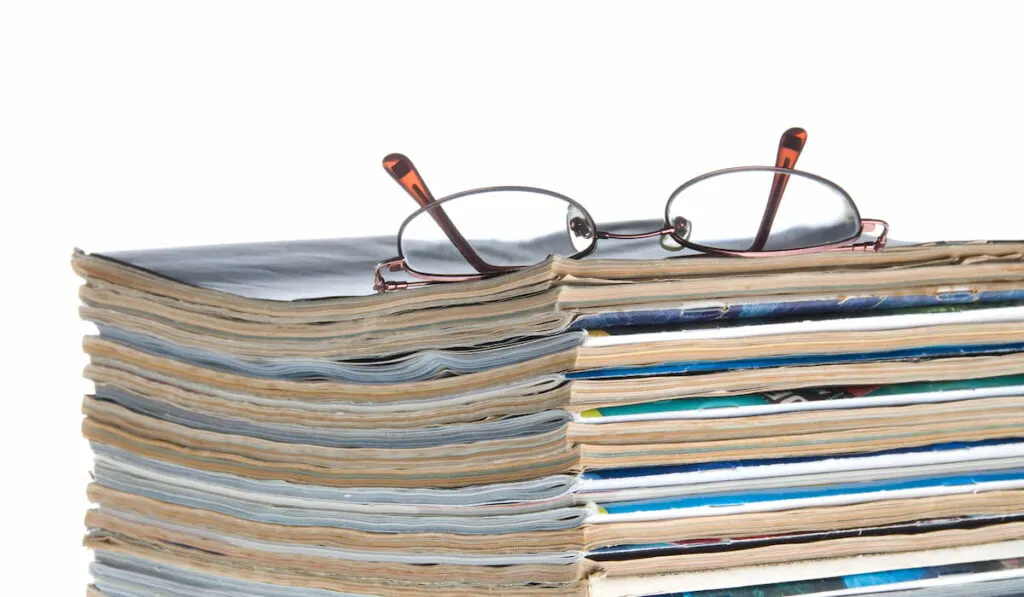 stack of old worn magazines with a pair of glasses on top