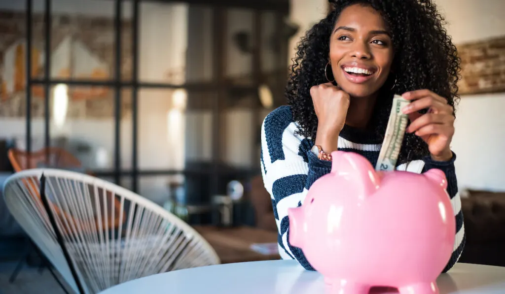 woman with saving money on her pink piggy bank